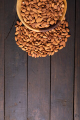 Directly above shot of fresh nutritious almonds in wooden bowl on table with empty space