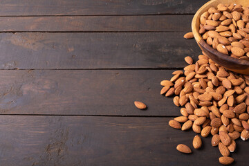 High angle view of nutritious almonds in wooden bowl on table along empty space