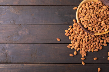 Overhead view of fresh healthy almonds in wooden bowl on table with empty space