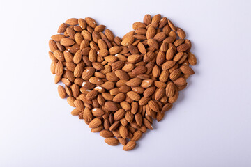 Directly above shot of almonds arranged in heart shape pattern on wooden white background