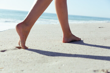 Feet of a Caucasian woman walking on sand and enjoying at beach