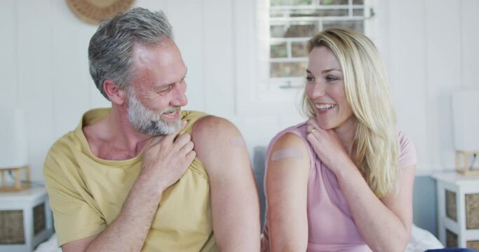 Happy caucasian mature couple showing plaster on arm where they were vaccinated against coronavirus