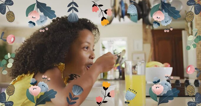 Animation of flowers over african american girl eating breakfast at home