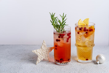 Two colorful Christmas cocktails in glasses on white table. Assortment of fresh holiday drinks. Red sangria cocktails, orange punch cocktail, tropical mule.