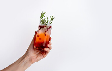 Woman's hand holding сranberry gin tonic on white background. Fresh holiday drink. Copy space.