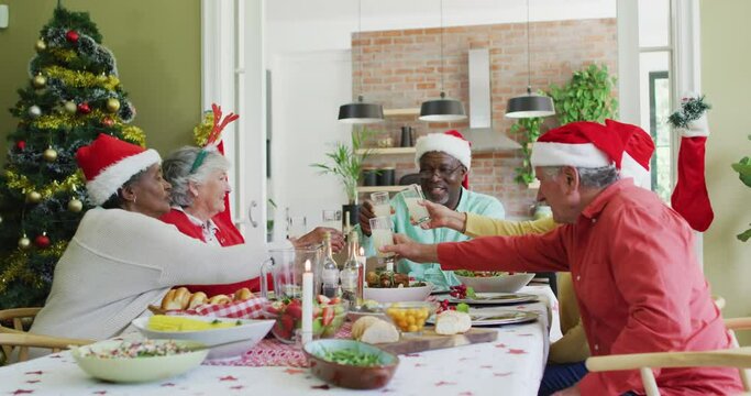 Happy group of diverse senior friends celebrating meal and drinking juice at christmas time