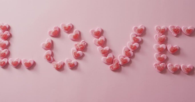 Love text of heart shape sweets on pink background at valentine's day