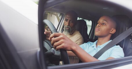 Video of focused african american father learning son how to drive a car - Powered by Adobe