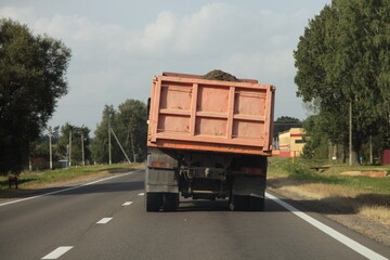 Heavy overloaded curvy dumper truck drive with bulk cargo on a European countryside asphalt road at summer day © Ilya