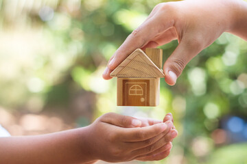 hand is giving a model of a house to child's hand, Concept for Investing in long-term real estate for the future. Inheritance concept.  Inherited property idea. - obrazy, fototapety, plakaty