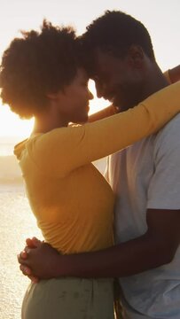 Smiling african american couple embracing in water on sunny beach