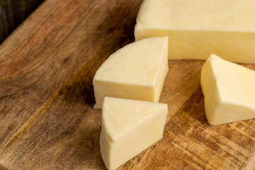 Fresh cow's milk cheese is cut on a board