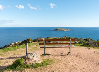 A single empty wooden bench looking out to an isolated island in the Southern Ocean