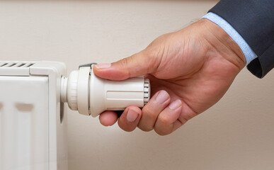 Man's hand adjusting the temperature of a radiator. Suitable for natural gas hike news, close up