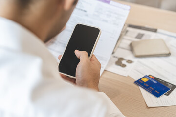 Cost, budget asian young man calculate expense, spending and check from invoice, use smartphone, mobile phone pay payment internet online of credit card at home. Technology of finance, financial.