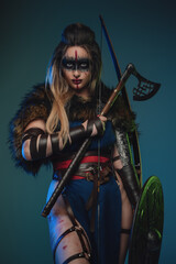 Photo of nordic huntress woman with strup back longbow holding shield and axe. - obrazy, fototapety, plakaty