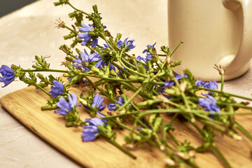 a mug with a drink and chicory flowers on a cutting board
