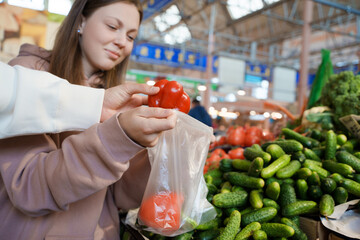 Shot of glad couple of man and woman byuing fresh peppers in vegetable store in bazaar.