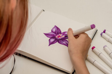 Hand drawing a purple flower sketch in a sketchbook with alcohol based sketch drawing markers.