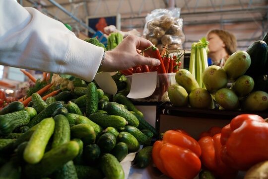Shot of buyer man taking pepper from vegetable stall of shop in marketplace.