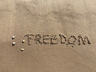 on the beach is carved with letters in the smooth sand the writing freedom