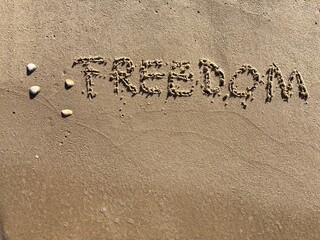 on the beach is carved with letters in the smooth sand the writing freedom