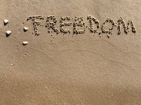 on the beach is carved with letters in the smooth sand the writing freedom