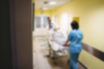 Doctor pushing patient in hospital bed through corridor