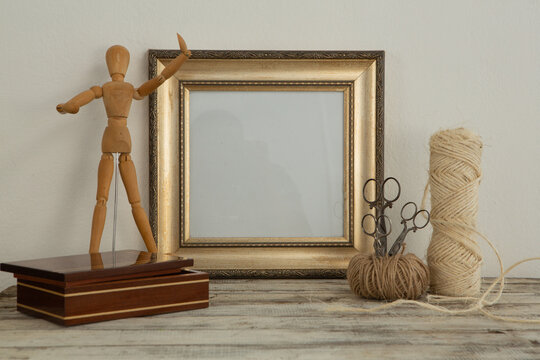 Photo frame, wooden mannequin and thread roll on table