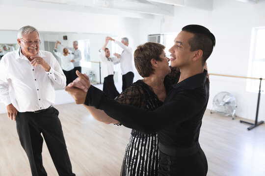 Mixed race dance teacher helping his ballroom dancing class