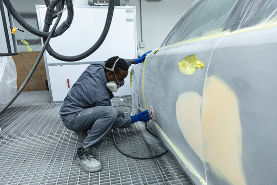 African American man car painter sanding a car