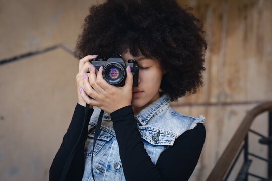 Mixed race woman taking pictures with camera on a staircase