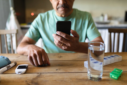 Senior african american man sitting by table using smartphone
