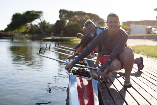 Portrait of senior caucasian rowing team holding the boat while sitting on the wooden dock