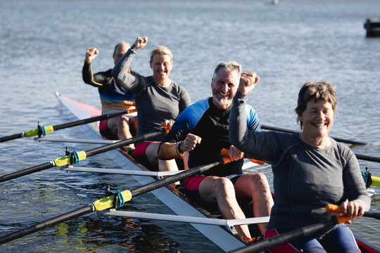 Senior caucasian rowing team having fun while rowing the boat on the lake