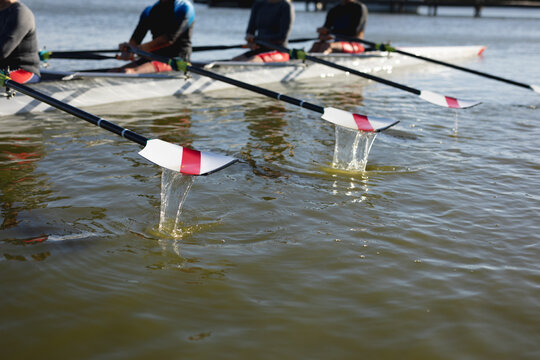 Mid section of senior caucasian rowing team rowing the boat on the lake