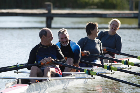 Senior caucasian rowing team smiling while rowing the boat on the lake