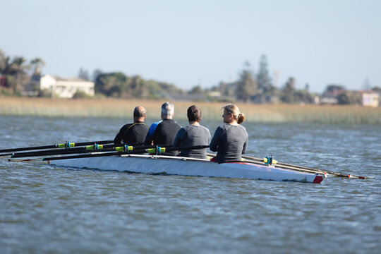 Rear view of senior caucasian rowing team rowing the boat on the lake