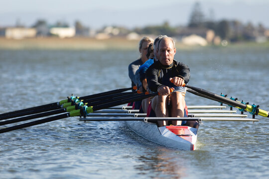Senior caucasian rowing team rowing the boat on the lake
