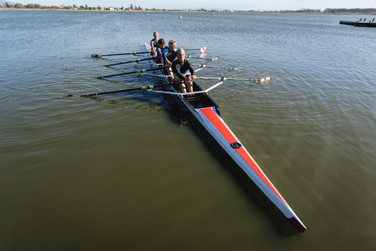 Senior caucasian rowing team rowing the boat on the lake