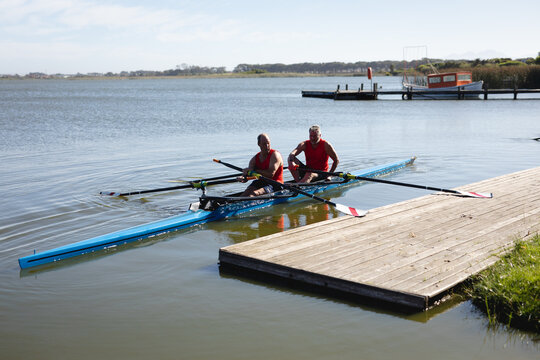 Two senior caucasian male rowers rowing the boat on the lake