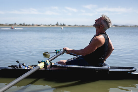 Senior caucasian male rower rowing the boat on the lake