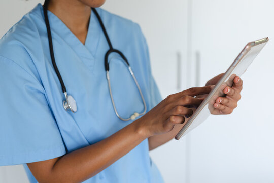 Close up of mixed race female doctor home visiting using tablet