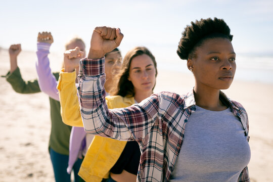 Group of diverse female friends raising fists standing on the beach