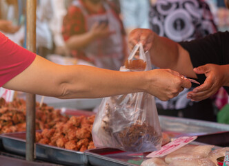 Woman hand hold money to buying fire fish and other food.