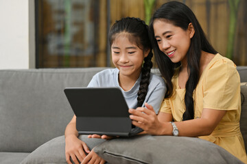 Happy loving family. Asian mother and her daughter girl are having fun with digital tablet.