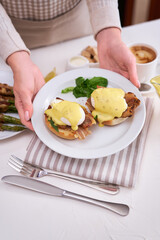 Tasty eggs Benedict, hollandaise sauce and aspargus covered with bacon
