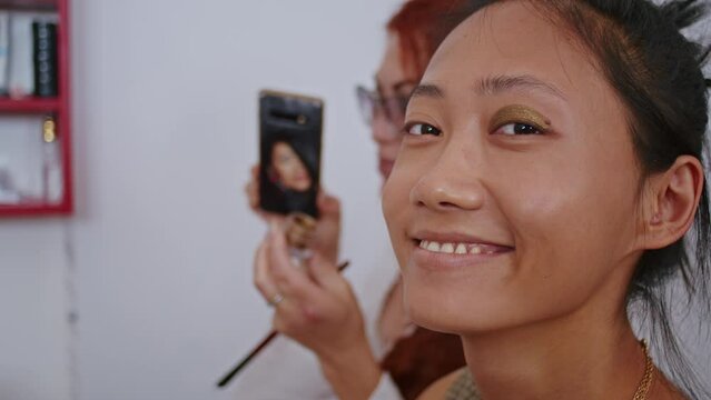 happy vietnamese woman stylist and european woman makeup artist are working on creating an image for. close-up. Asian woman and work as a stylist.