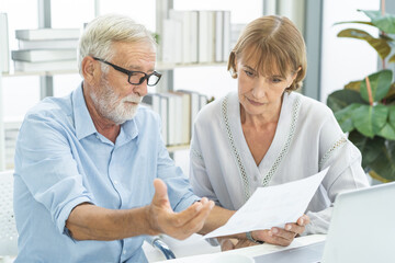 Fototapeta premium Stressed husband, wife senior couple elderly family, caucasian mature, retired calculate budget from invoice, expense or bill, no money to pay. Mortgage, loan causing debt, bankruptcy of financial.
