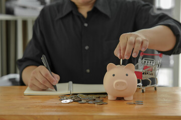 Obraz na płótnie Canvas ฺBusinessman saving money by putting a coin into piggy bank concept saving money for finance accounting 